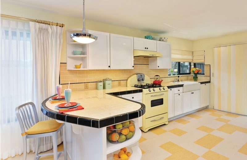 Retro kitchen with yellow tile and stove and black accents.