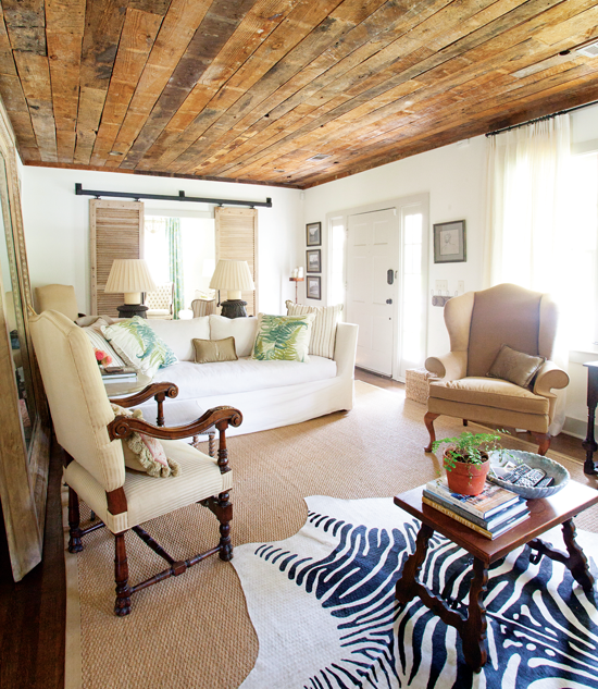 Reclaimed woodworking covers the ceiling of this living room, with natural colored design elements and a zebra rug under the coffee table. 