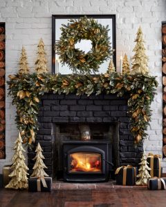 a black fireplace with gold wood trees on the mantel and hearth and a generous gilded Magnolia swag on the mantel.