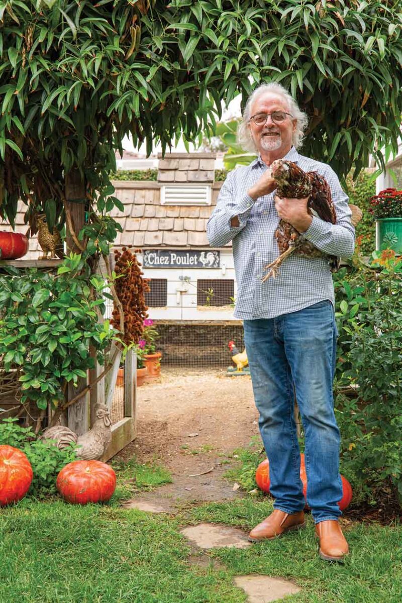 homeowner Mitch Berry holding chicken outside his home's chicken coop