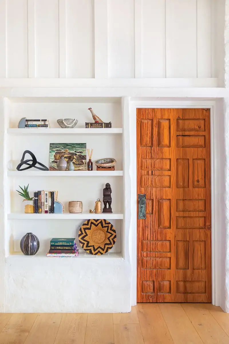 styled bookshelf next to wood door with rectangular carving