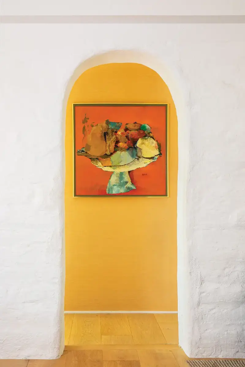 adobe archway frames orange accent wall and painting in 1940s beach cottage