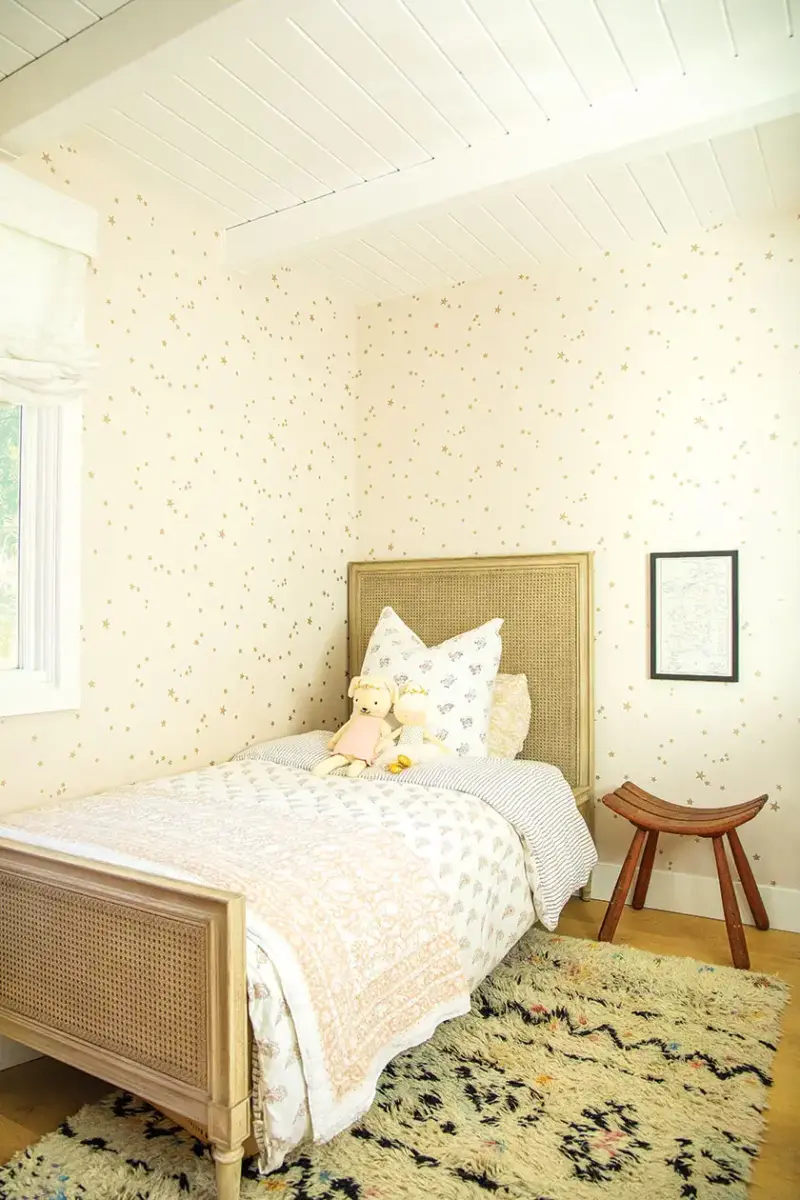 star wallpaper in girl's bedroom with textured rug and cane style bedframe