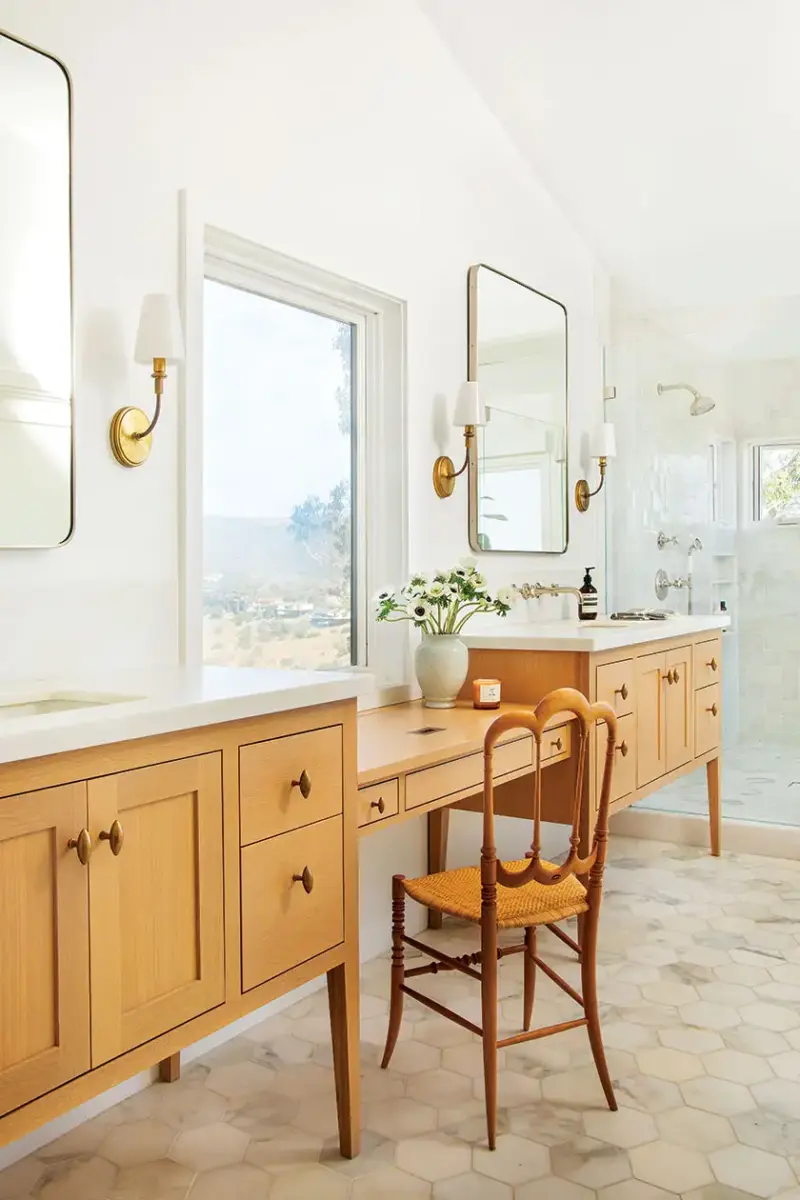 spacious master bath with hexagonal tiles in cream and wood cabinetry in vanities