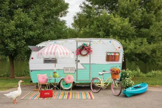 colorful camper from the outside with white duck and colorful bistro set and rug and bike