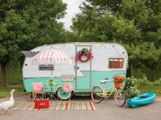 colorful camper from the outside with white duck and colorful bistro set and rug and bike