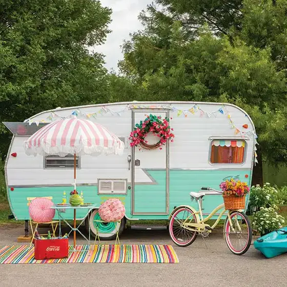 colorful camper from the outside with white duck and colorful bistro set and rug and bike