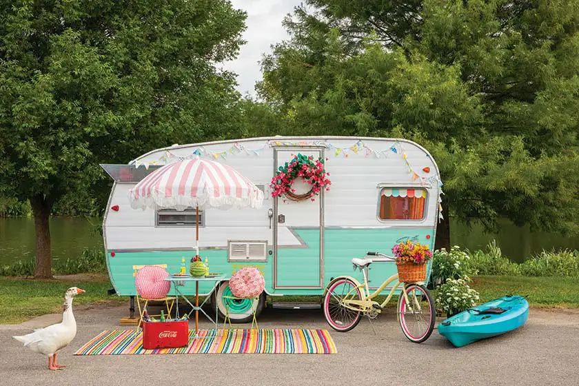 colorful camper from the outside with white duck and colorful bistro set and rug and bike