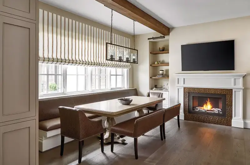 long built in bench seating in neutral dining room with browns and beiges and fireplace