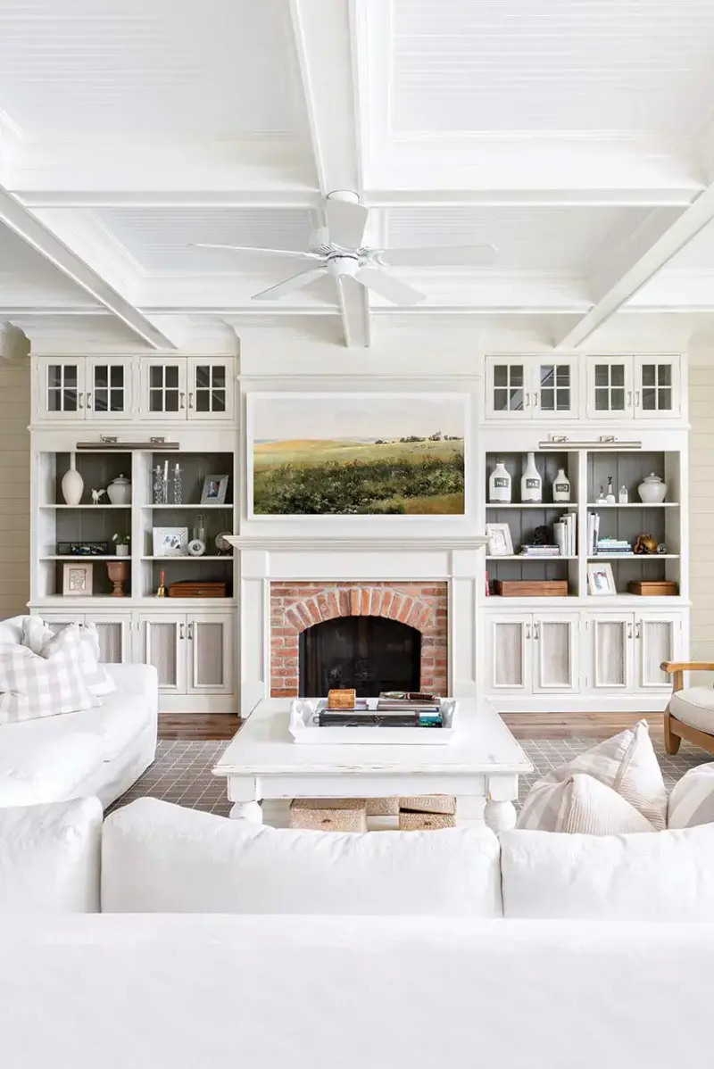 view of living room showing two built-in shelving units with dark gray backs and white fronts