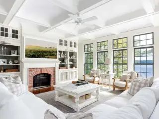 lakeside farmhouse cottage living room with lake view fireplace landscape painting and white color scheme