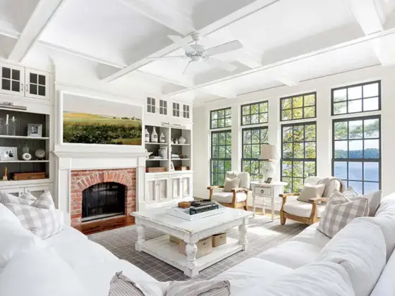 lakeside farmhouse cottage living room with lake view fireplace landscape painting and white color scheme