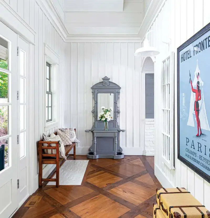 gray mirrored cabinet in entryway with wooden bench and wooden floors in entryway of Bellamere