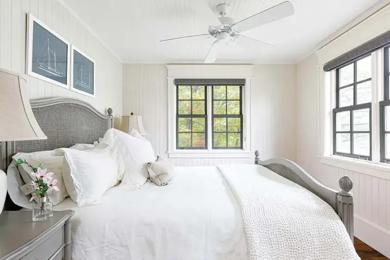 black window frame with gray bedframe and white bedding in lakeside cottage farmhouse