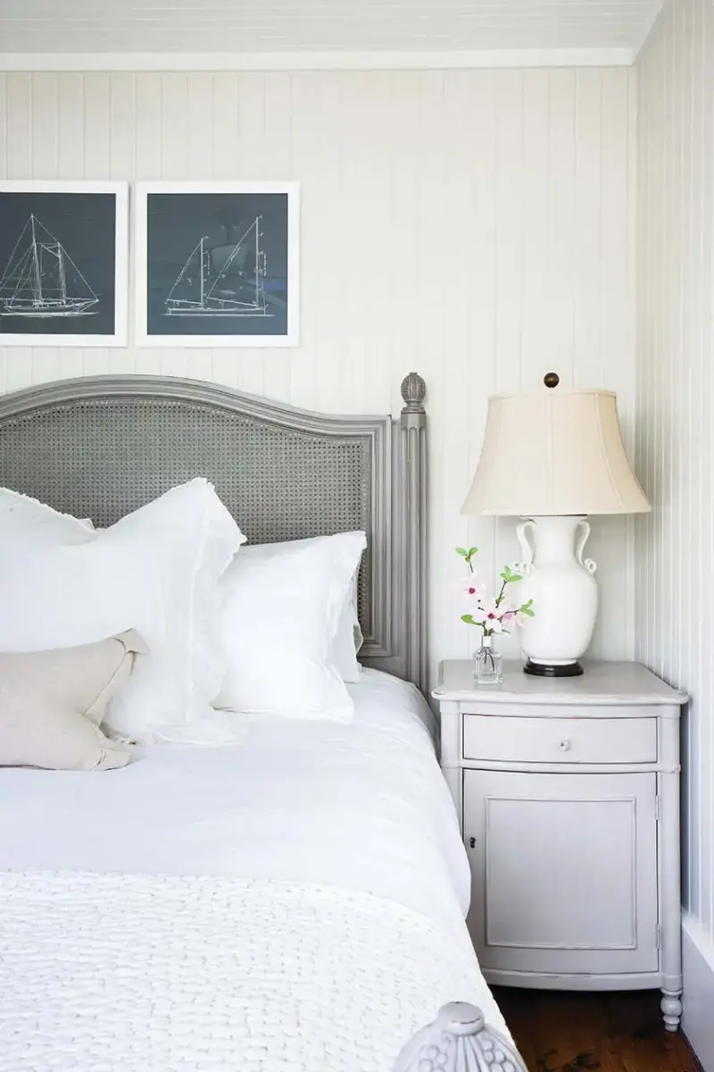 gray cane headboard with white beadboard walls and black and white sailboat drawings