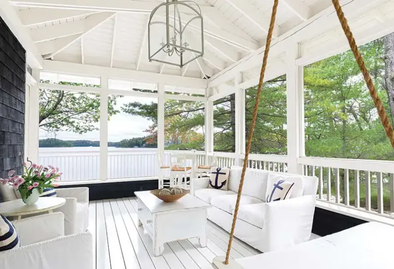 covered patio with white roof, porch swimg, white seating and view overlooking Lake Muskoka