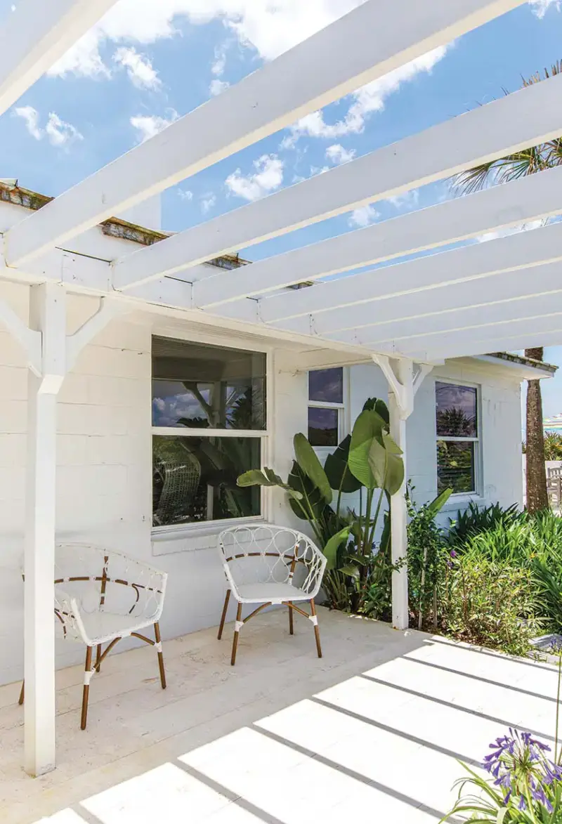 pergola with white woven chairs and landscaping