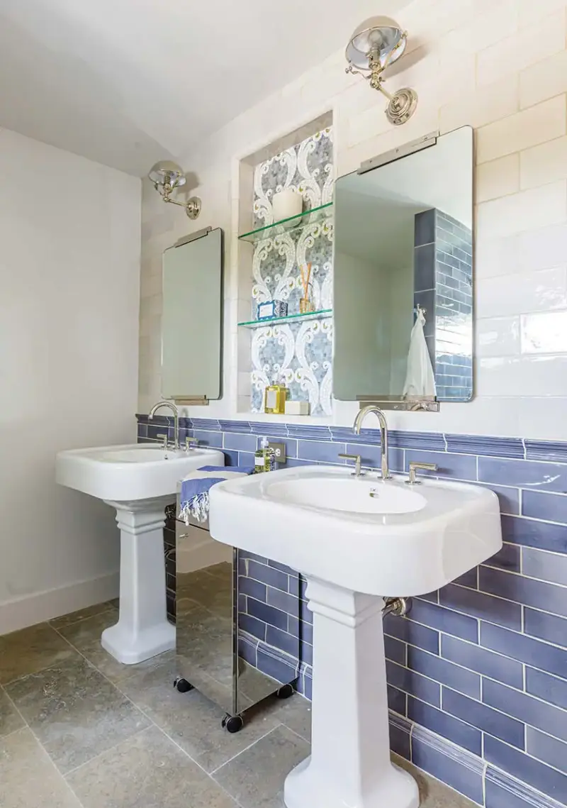 blue ceramic tile half wall and two vintage pedestal style sinks