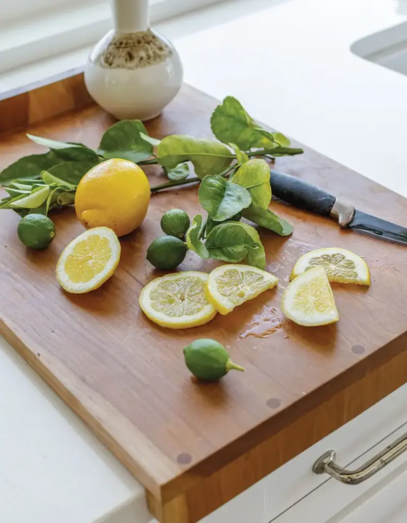 pastry cutting board with lemons and limes on white kitchen counter