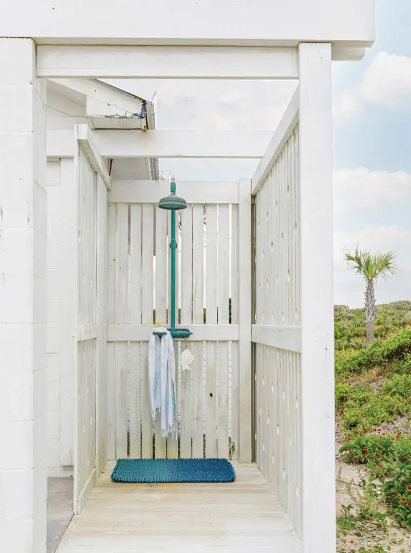 outdoor shower with teal shower head and mat