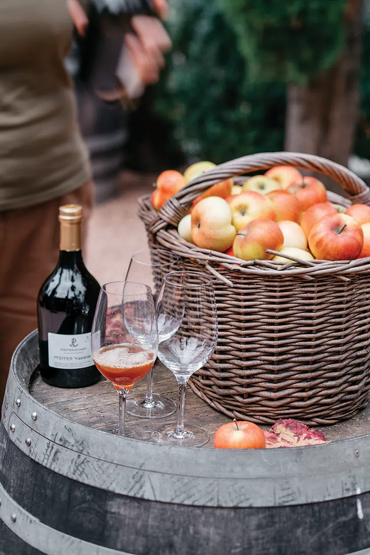 basket full of apples next to a bottle of wine