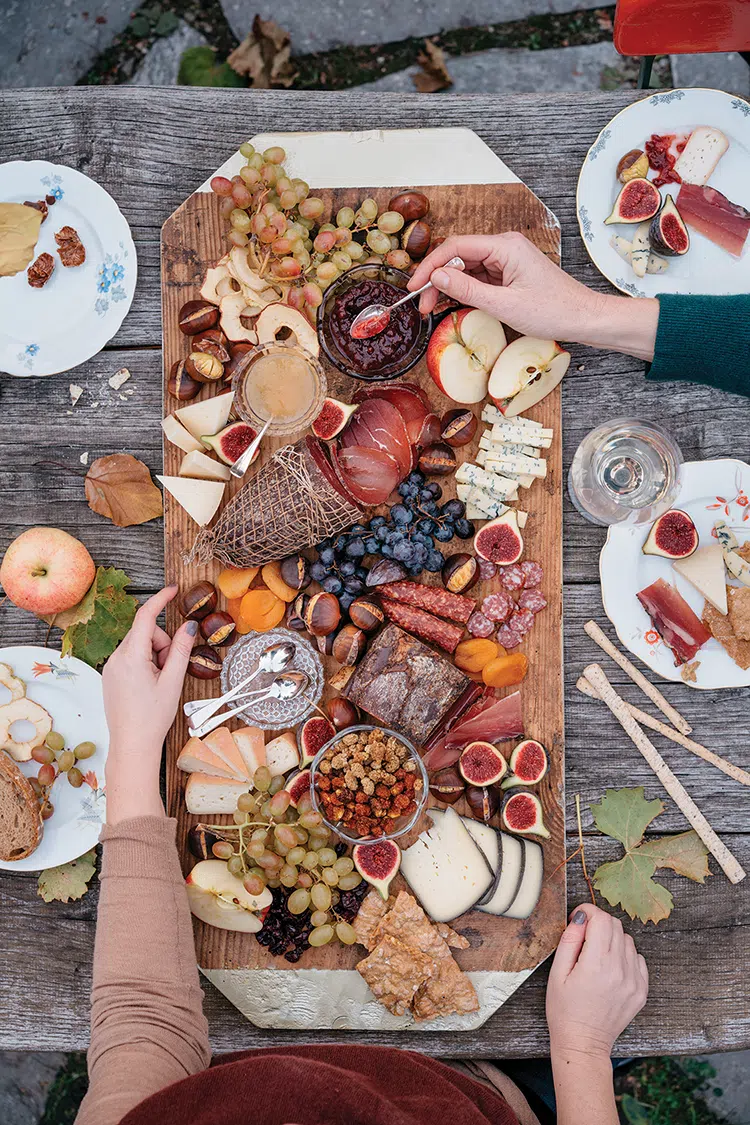 charcuterie board with grapes, apples, cheeses, nuts, figs and cured meats for outdoor fall feasting