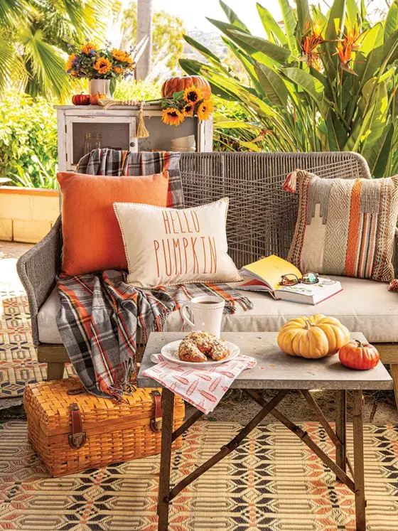 outdoor nook in California garden with cozy seating area with orange throw pillows and table with decorative pumpkins and almond croissant