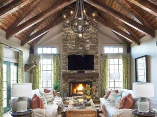 living room with rounded metal chandelier layered rugs and warm fire in rustic Craftsman cottage with modern touches