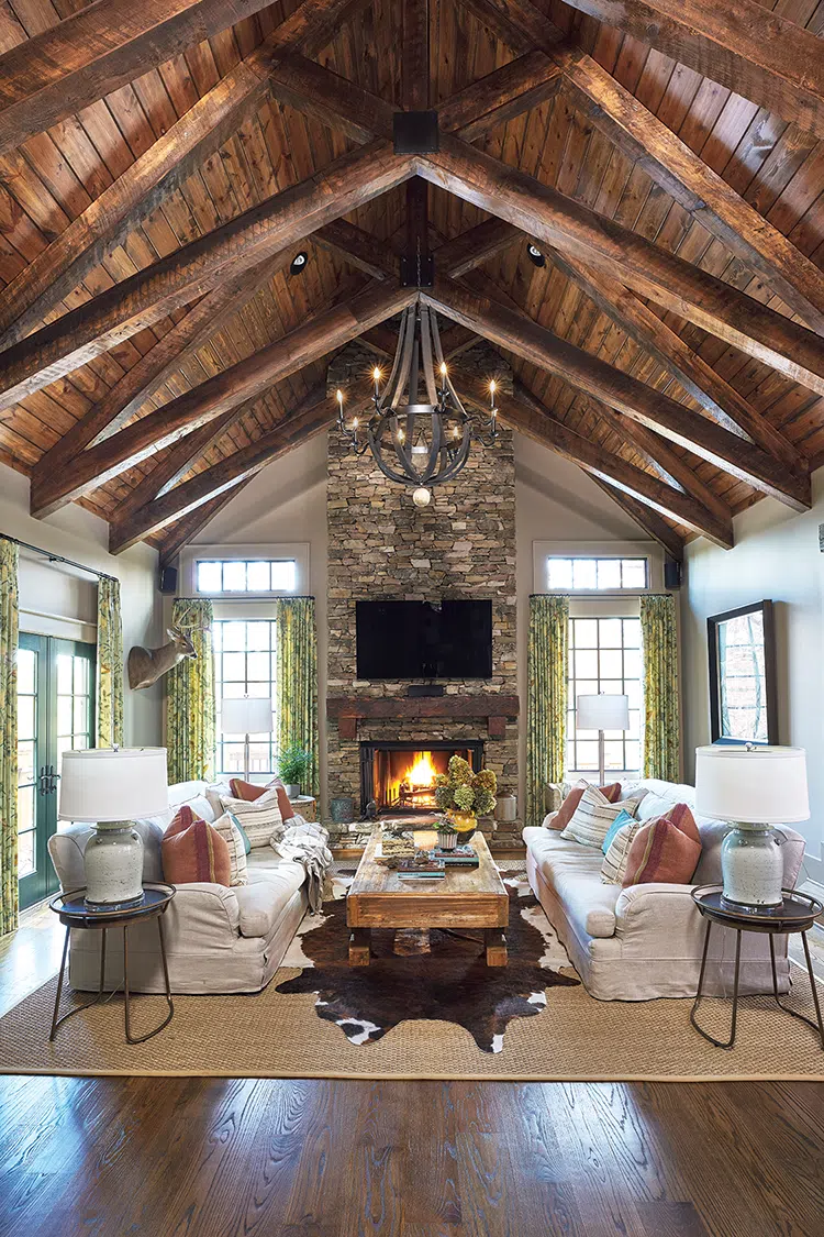 living room with rounded metal chandelier layered rugs and warm fire in rustic Craftsman cottage with modern touches