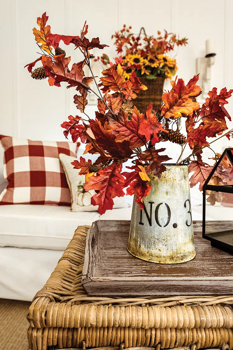 vignette of faux fall leaves in galvanized pitcher in cozy cottage