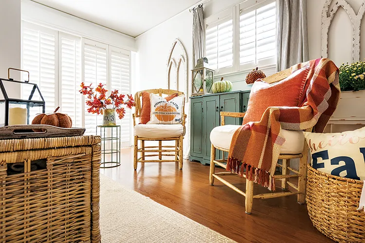 cozy cottage fall sitting area with orange throws, pumpkin throw pillow and decorative fabric and real pumpkins