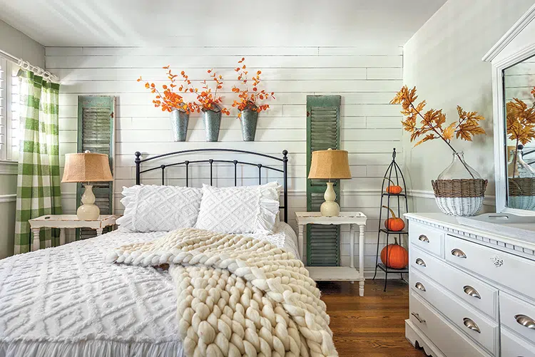 cozy cottage fall with faux fall branches in hanging galvanized vases above bed