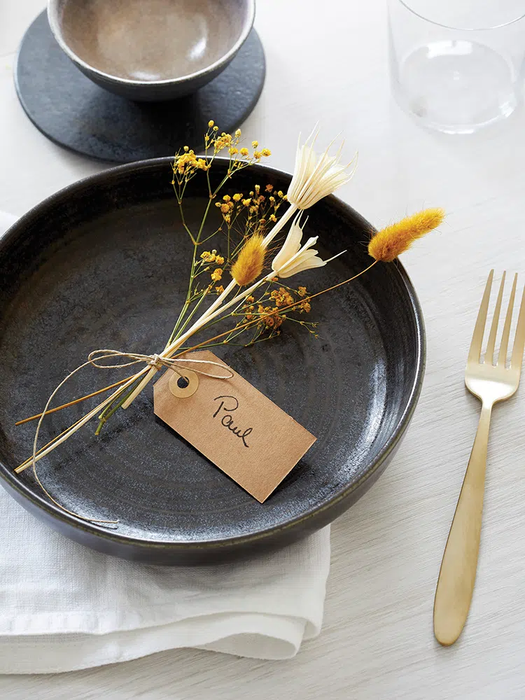 handmade place setting with handwritten tag attached to small bouquet of dried grasses and flowers