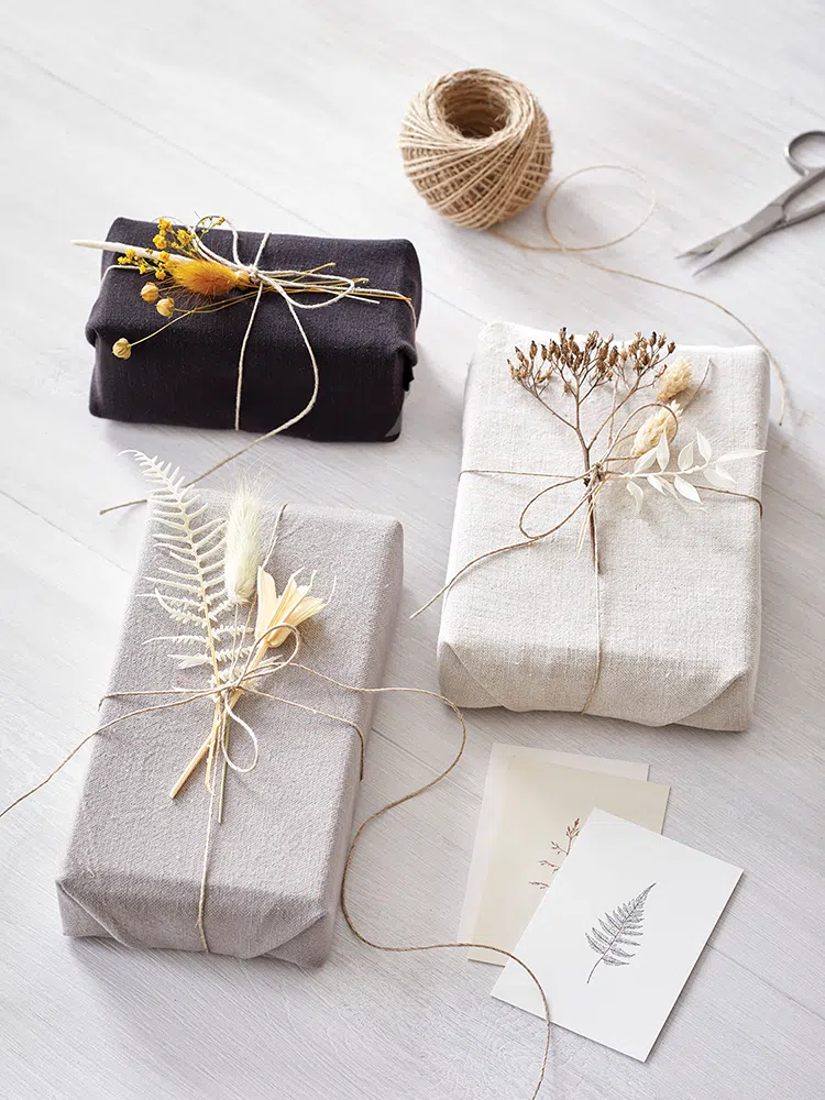 gifts wrapped in fabric and finished with dried plants tied with twine