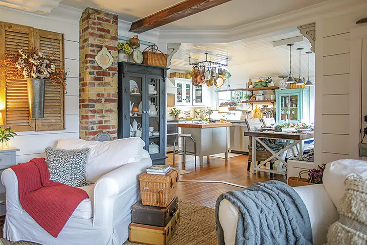 living room with view to kitchen with bistro style pot and pan storage, exposed wooden shelves and white living room furniture