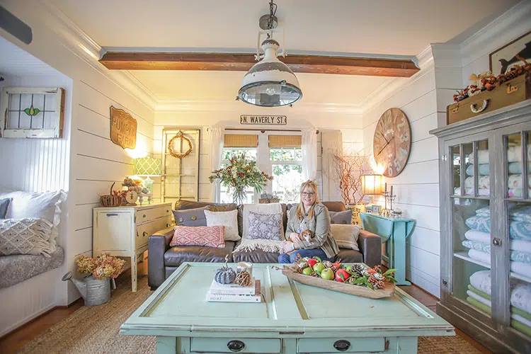 living room decorated for fall with tray of apples and pinecones, watering can with dried hydrangeas