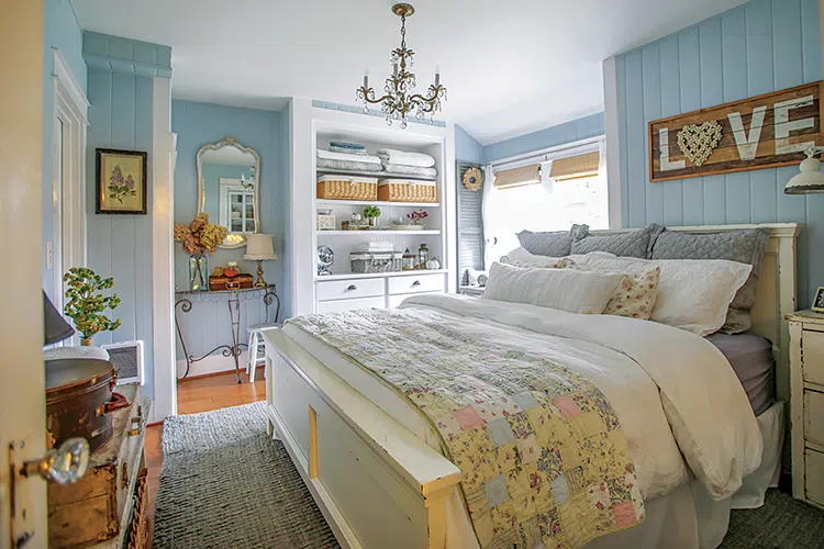 powder blue bedroom with chandelier and pastel colored quilt