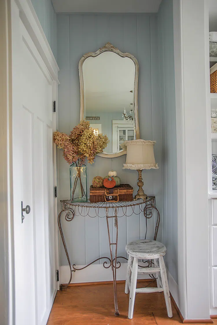 hallway vignette with vintage mirror, dried hydrangeas and decorative pumpkins on wire side table