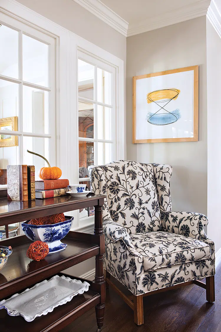 reading nook with neutral botanical patterned wingback chair, abstract art and storage shelves in traditional kitchen