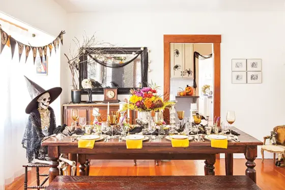 spooky and sophisticated Halloween dinner party tablescape with skeleton wearing black detailed shawl and witches hat