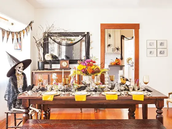 spooky and sophisticated Halloween dinner party tablescape with skeleton wearing black detailed shawl and witches hat