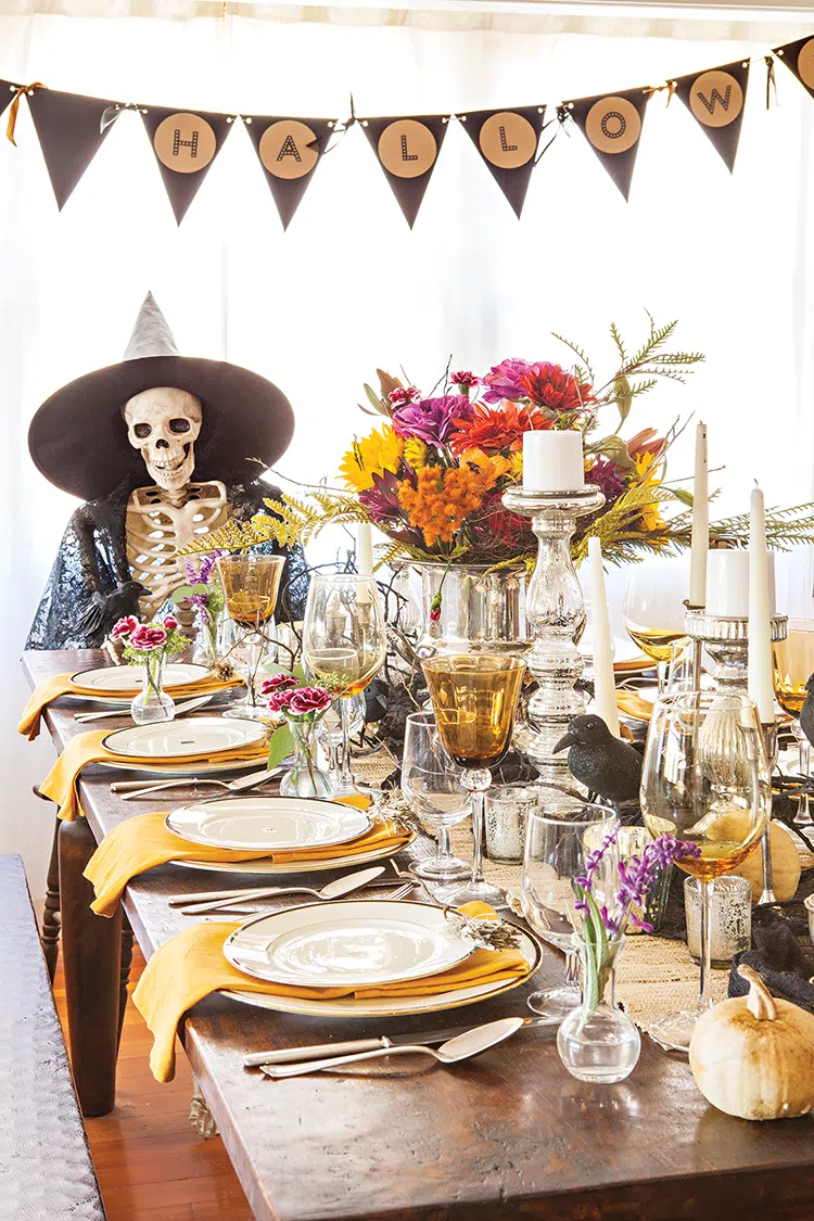 floral bouquet fake crows silver candlesticks and fake skeleton comprise tablescape for spooky and sophisticated Halloween