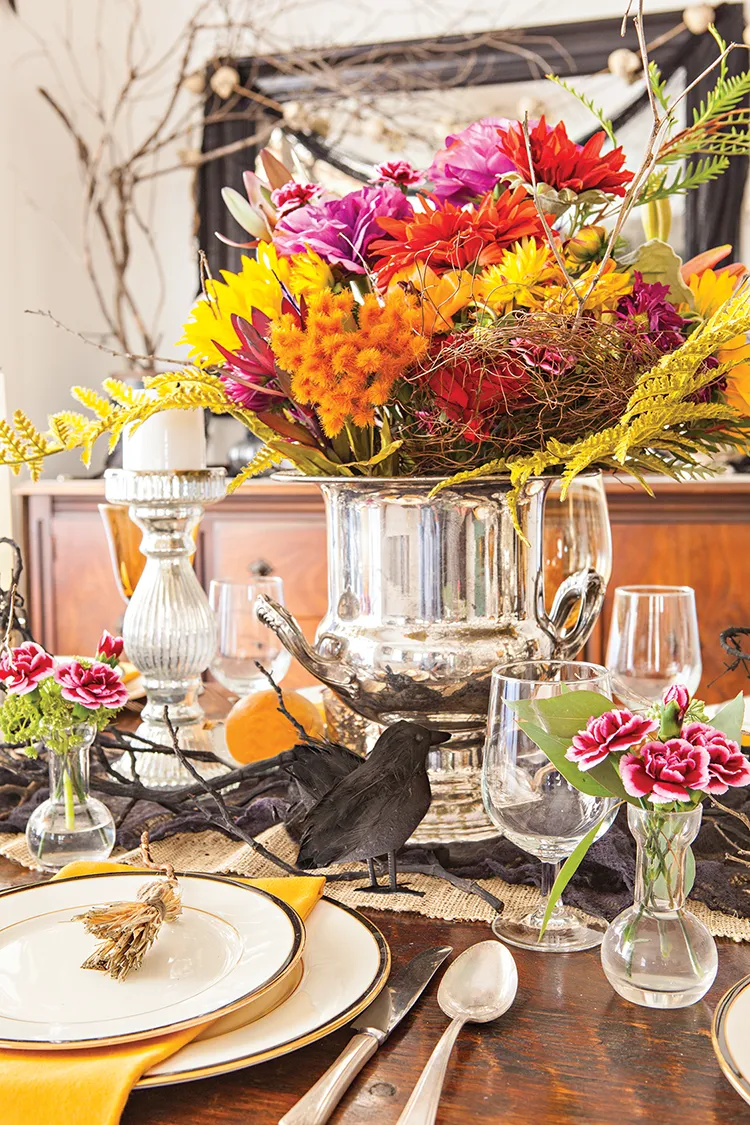 floral bouquet in fall colors at center of table set for Halloween party