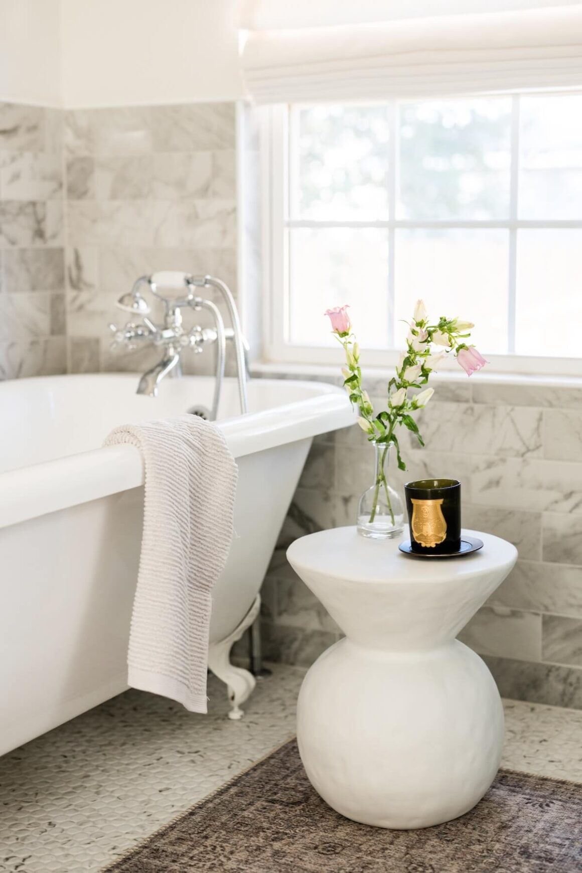 clawfoot tub with decorative stand in neutral bathroom