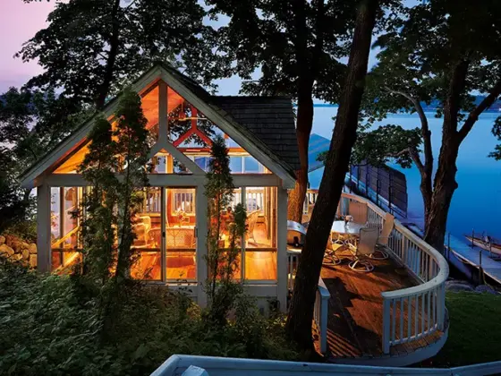 warm light emanating from lakeside home with floor to ceiling windows