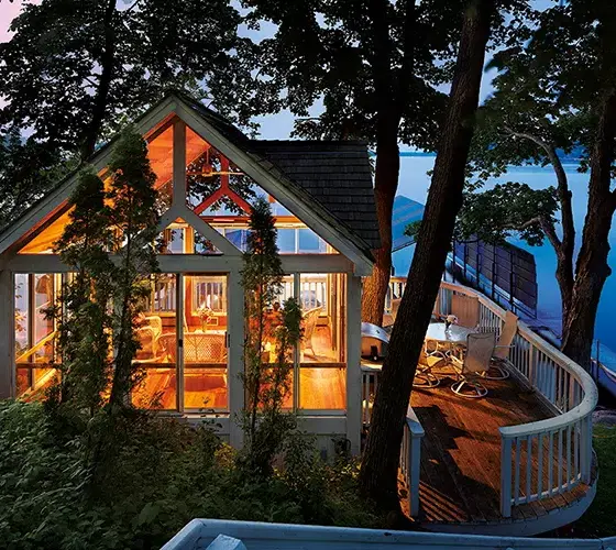 warm light emanating from lakeside home with floor to ceiling windows