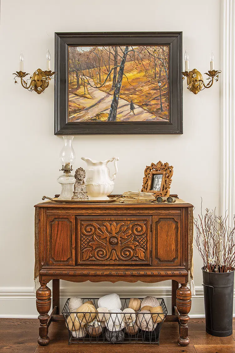 painting of a park in the fall in a Victorian home with vintage and antique objects and credenza