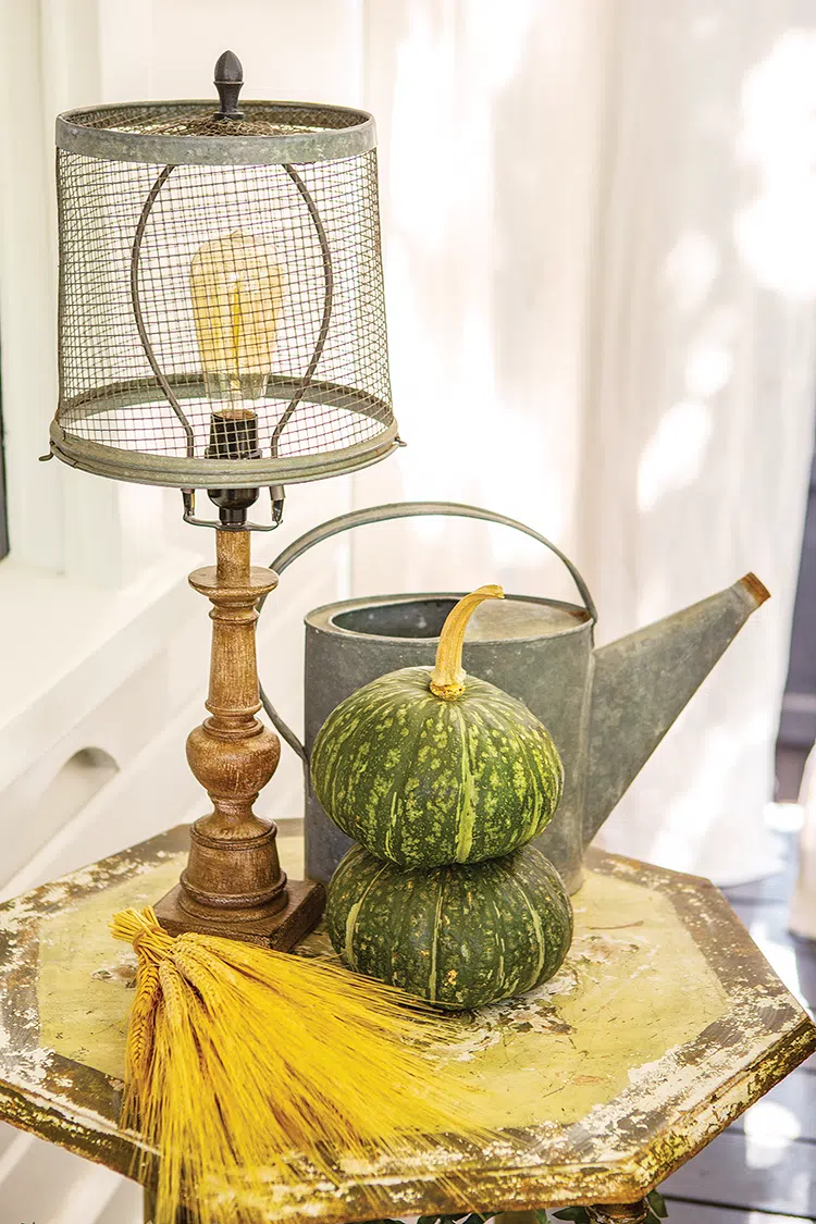 small bundle of wheat and green squash create a fall feel in addition to the vintage lamp and watering can