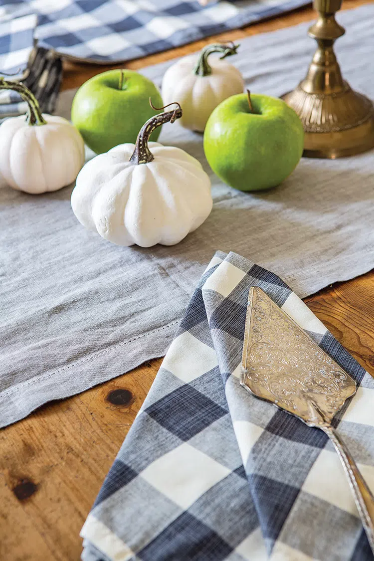 white pumpkins, green apples and silver cake lifter on dining table