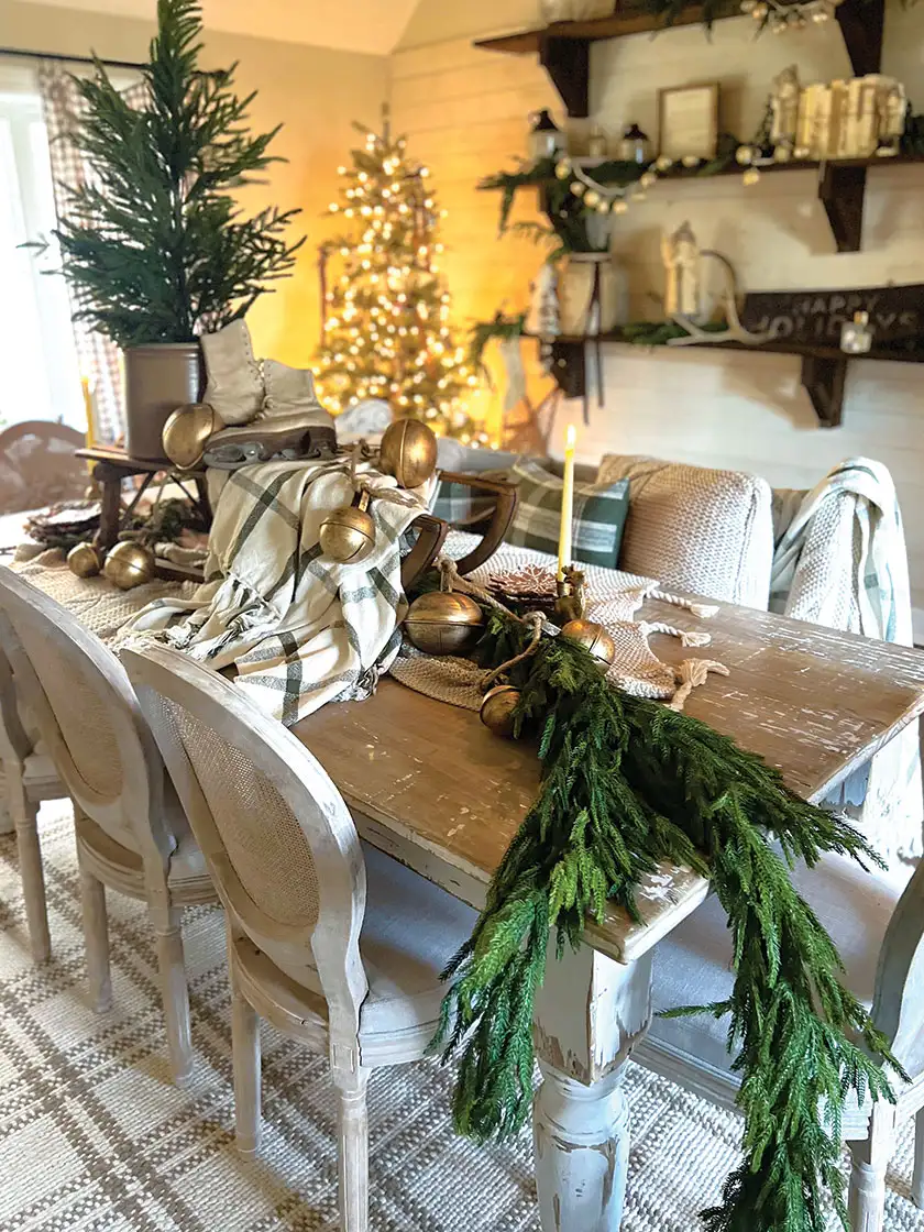 table with vintage sled styled with ice skates jingle bells and potted tree as centerpiece